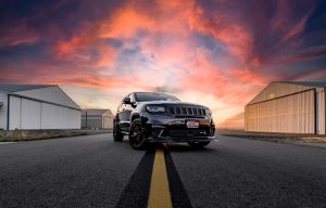 A black jeep grand cherokee is parked on an empty road.