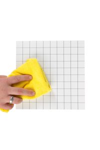 A person wiping a yellow cloth on a white grid.