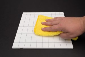 A person wiping a yellow cloth on a square grid.