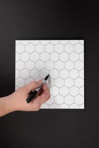 A hand holding a piece of paper with a hexagon pattern on it.