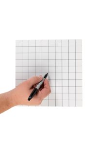 A person holding a pen on a grid paper.