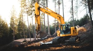 A yellow excavator in the woods.