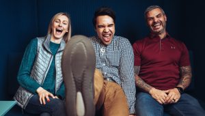 A group of people sitting on a couch laughing.