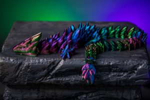 A colorful dragon laying on top of a rock.