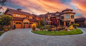 A large home with a driveway and a sunset sky.