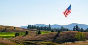 An american flag flies over a golf course.