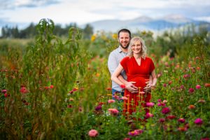 A pregnant couple standing in a field of flowers.