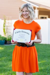 A woman in an orange dress holding a diploma.