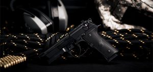 A black gun on a black background with headphones.