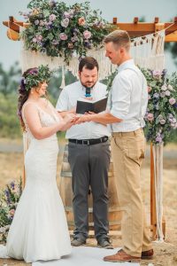 A bride and groom exchange vows at an outdoor vineyard wedding.
