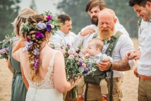 A man with a beard is holding a baby during a wedding ceremony.