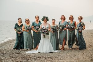 A bride and her bridesmaids pose on the beach.