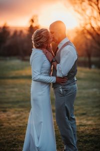 A bride and groom kissing at sunset in front of a golf course.