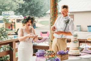 A bride and groom eating cake at an outdoor wedding.